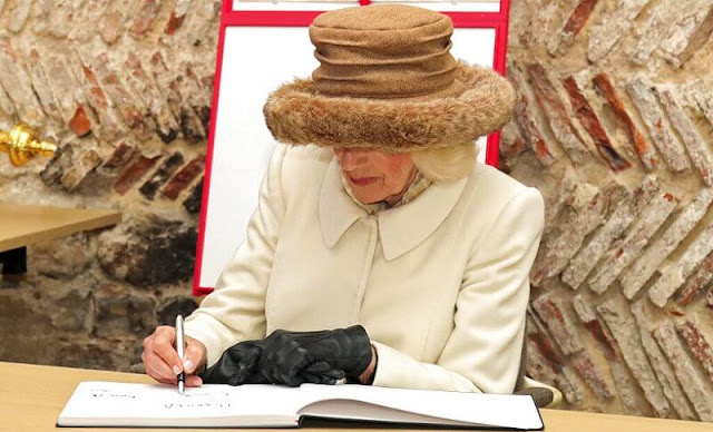 Queen Camilla wore a longline white ivory cashmere cream coat and she paired with a brown wide-brimmed fluffy hat