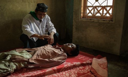 Abah Sanuk sedang mengobati salah seorang yang sakit jiwa dengan mantra-mantra mujarabnya