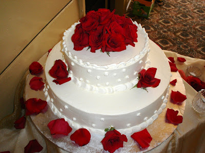 Red roses arranged on top of a white wedding cake with red roses and rose