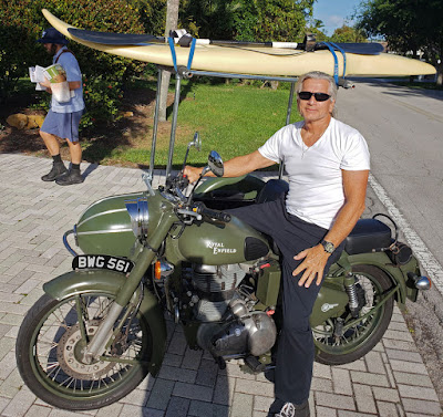 Motorcycle and sidecar with surfboard on top.