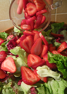 Cup of Sliced Strawberries Being Poured into Salad