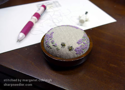 Embroidery mounted in pincushion base after being laced to the form