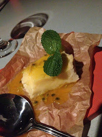 lemon and lime tart with sprig of mint and passion fruit sauce on paper on a board