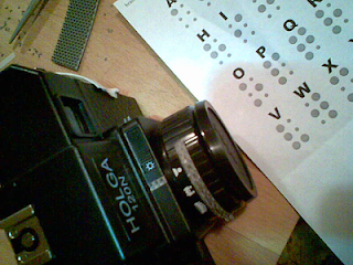 The rangefinder Holga, shot with my phone's camera, as I was modifying it on the kitchen counter. Braille letters, some Velcro(R) and Velcro(R) nibs are in the background.