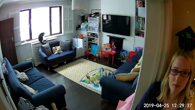 Still frame image from Neos SmartCam showing a front room and person with date stamp