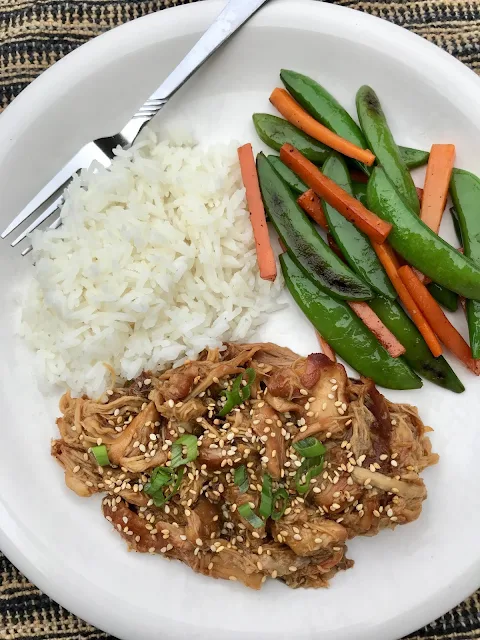Plate with honey sesame ginger chicken, rice, and stir fried vegetables for serving.