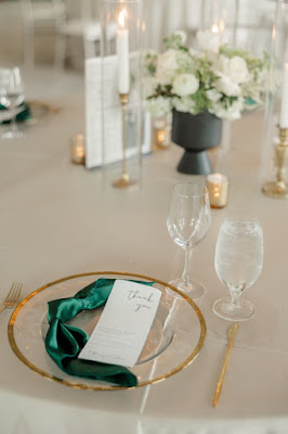 reception table setup with gold rimmed charger and emerald green knotted napkin