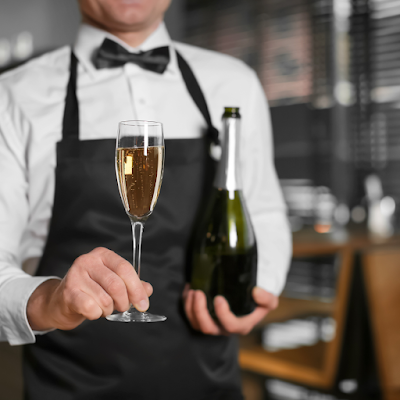 Waiter holding tray bottle and glass of champagne indoors