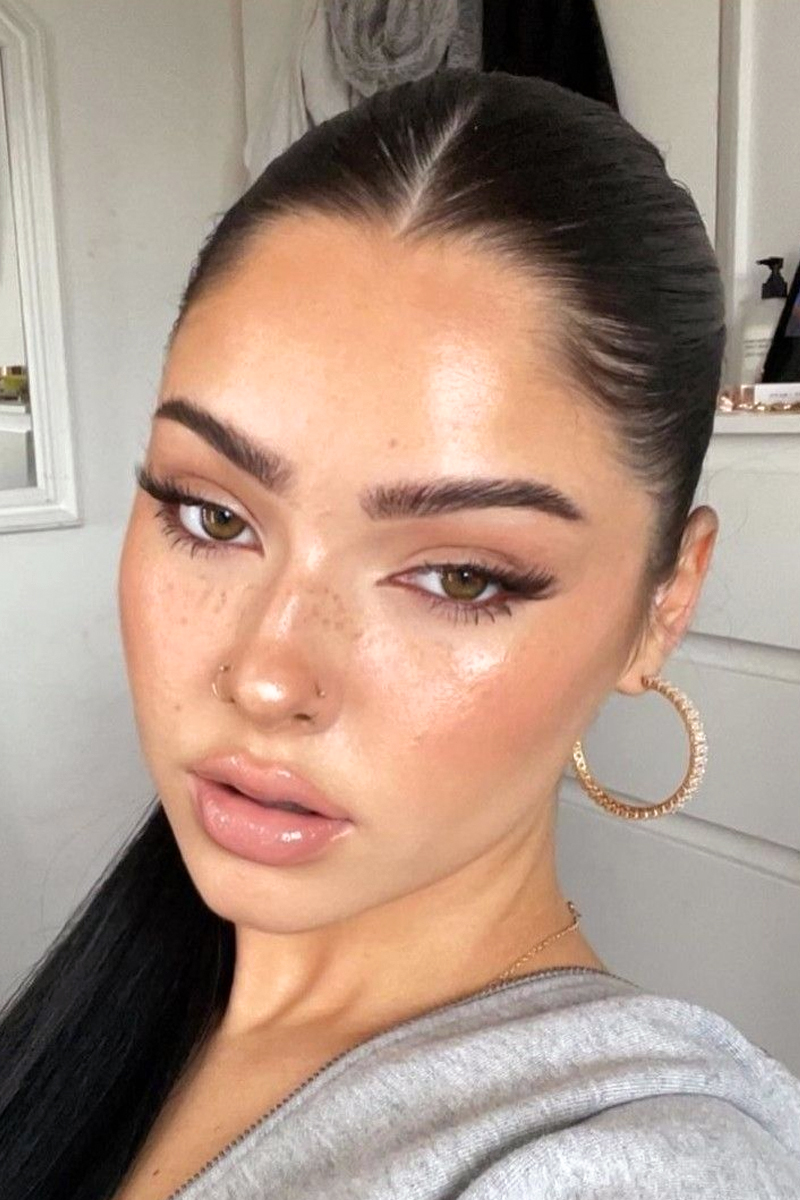 close-up selfie of a woman with dewy, clean girl makeup look and freckles on her face