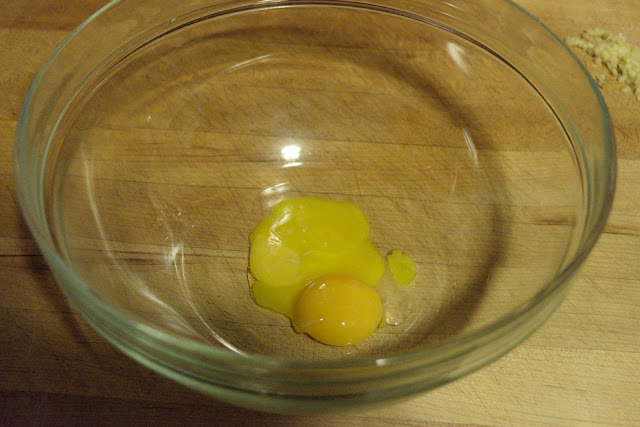 Two egg yolks being added to a mixing bowl. 