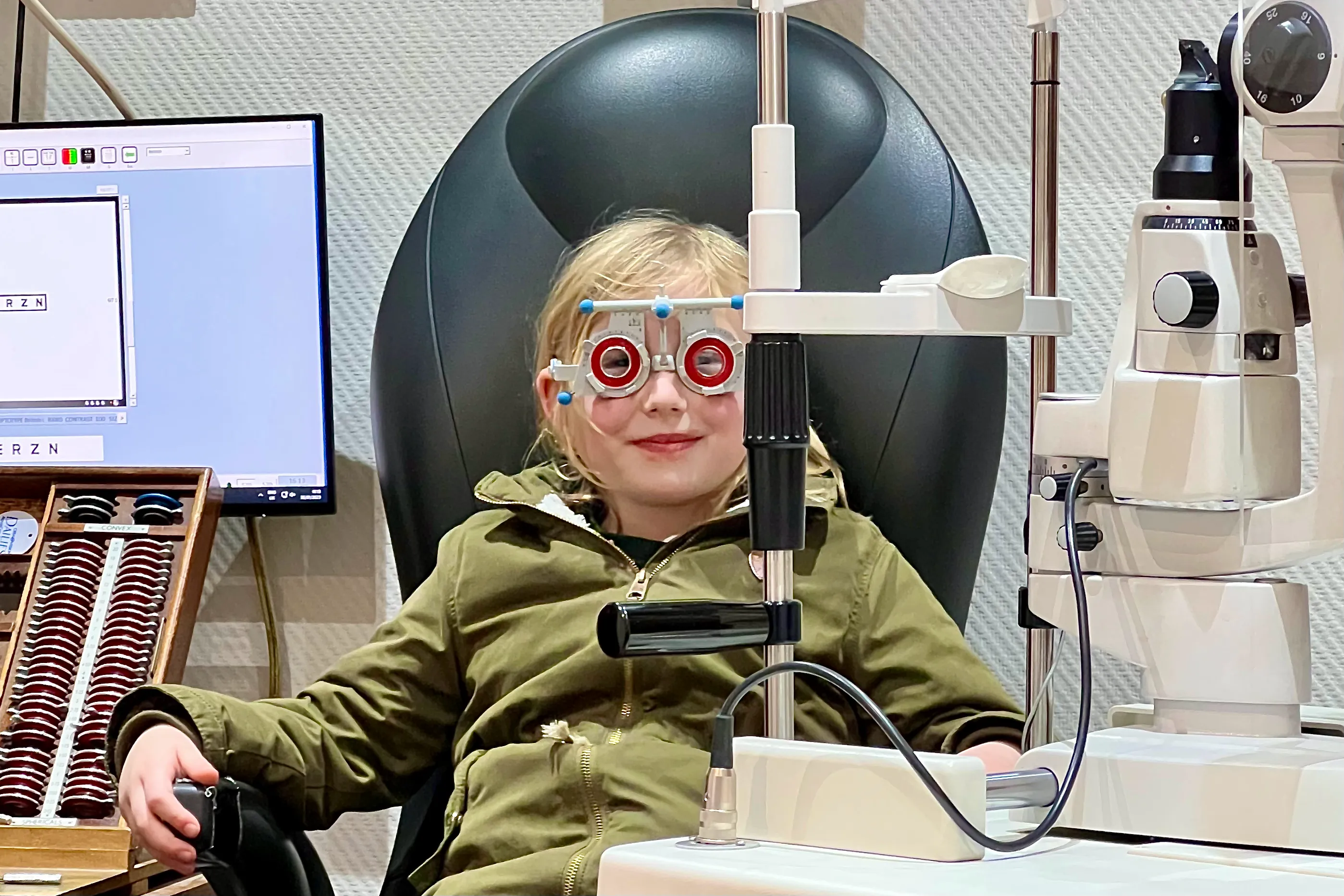 A child sitting in an opticians chair getting her eyes tested