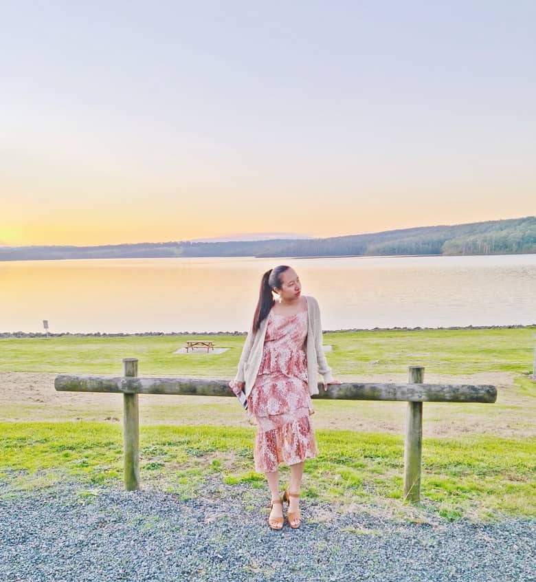 a girl wearing a dress overlooking a lake