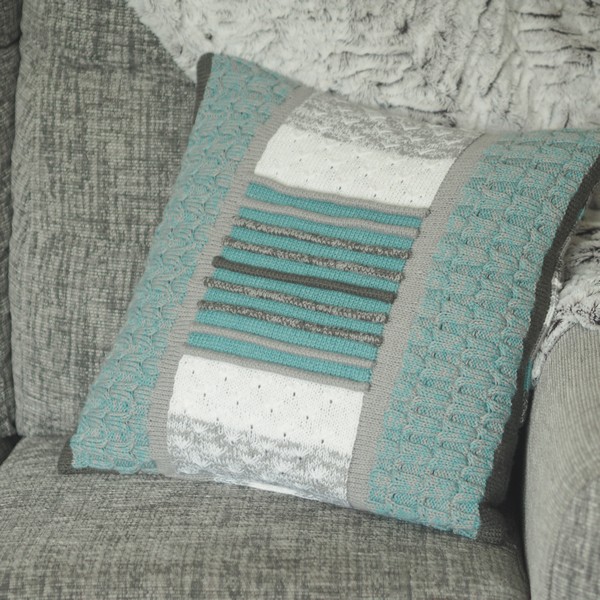 blue and grey knitted cushion on a grey sofa