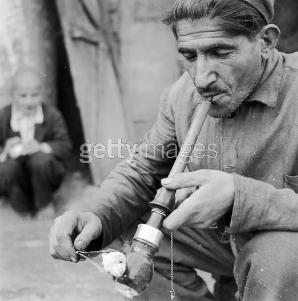 Opium Smoker circa 1950, An Iranian smoking an opium pipe. The pill of drug is heated with glowing coals and the resultant fumes inhaled with quick short puffs. (Photo by Three Lions:Getty Images).jpg