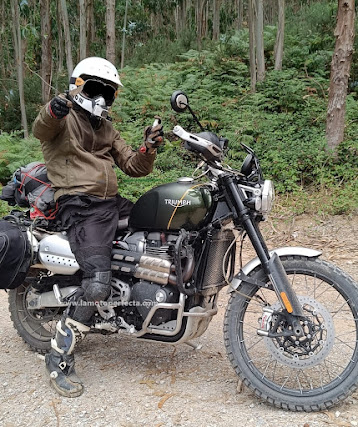 Él y su Triumph Scrambler 1200 XC piloto con navaja en mano moto trail botas enduro