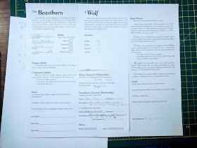 Two sheets of paper, one titled "The Beastborn" and the other "A Wolf," with various details of the characters on it 