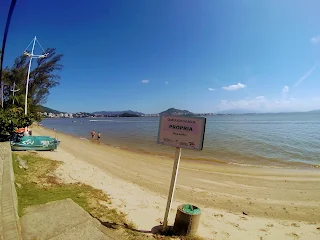 La playa de Cacupe Grande sin gente pero con unos botes, y un cartel indicando que el agua estaba apta para baño.