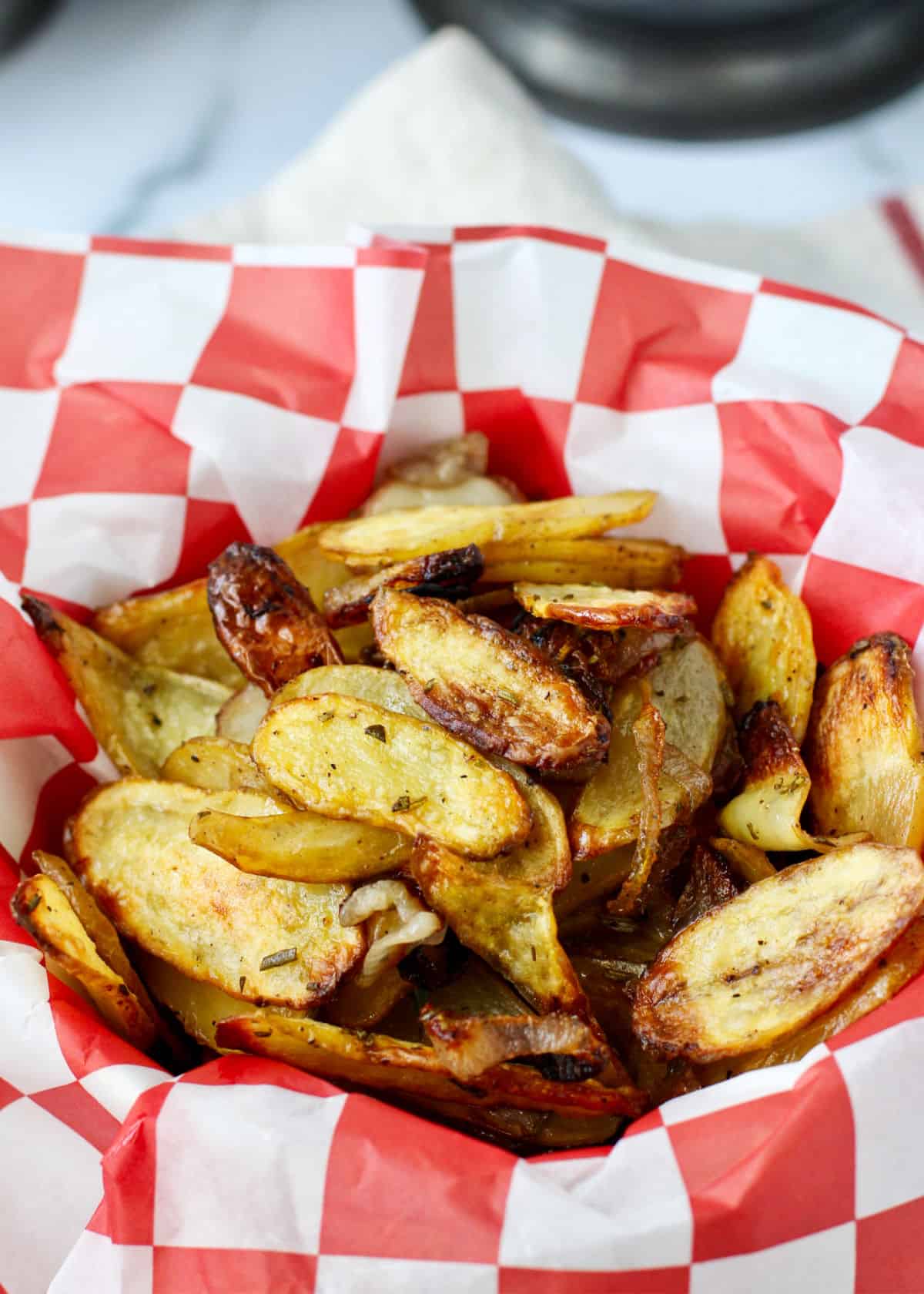 Roasted Fingerling Potatoes with Shallots and Rosemary in a red checkered paper lined bowl.