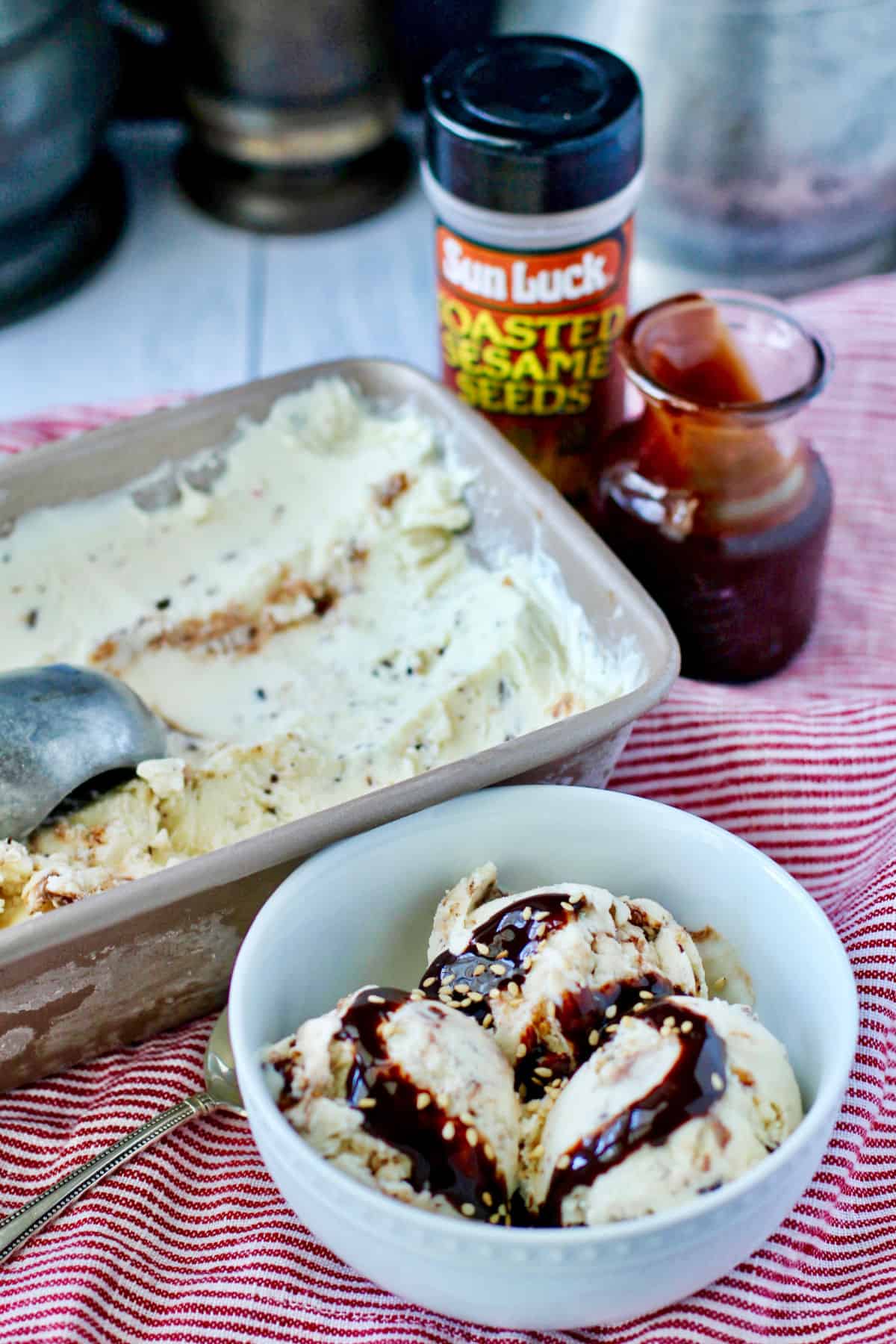 Tahini Chocolate Chunk No Churn Ice Cream in a bowl in front of a pan of the ice cream.