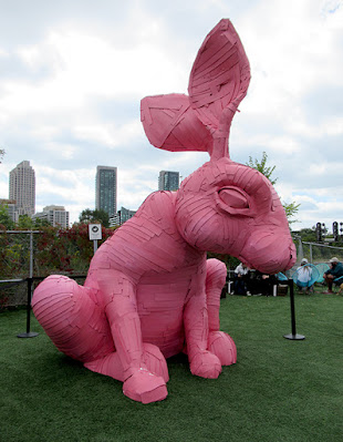 A large outdoor sculpture of a pink rabbit. Made from overlapping strips of material.