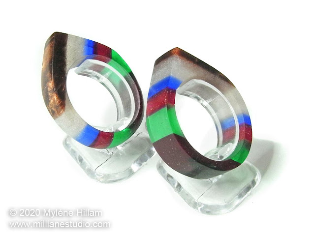 Two multicoloured striped resin rings shaped to a point