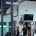 Man in black tank top lifting barbell at the gym