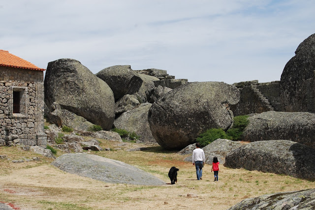 Padre, hija y perro paseando por la explanada del castillo, con la muralla al fondo