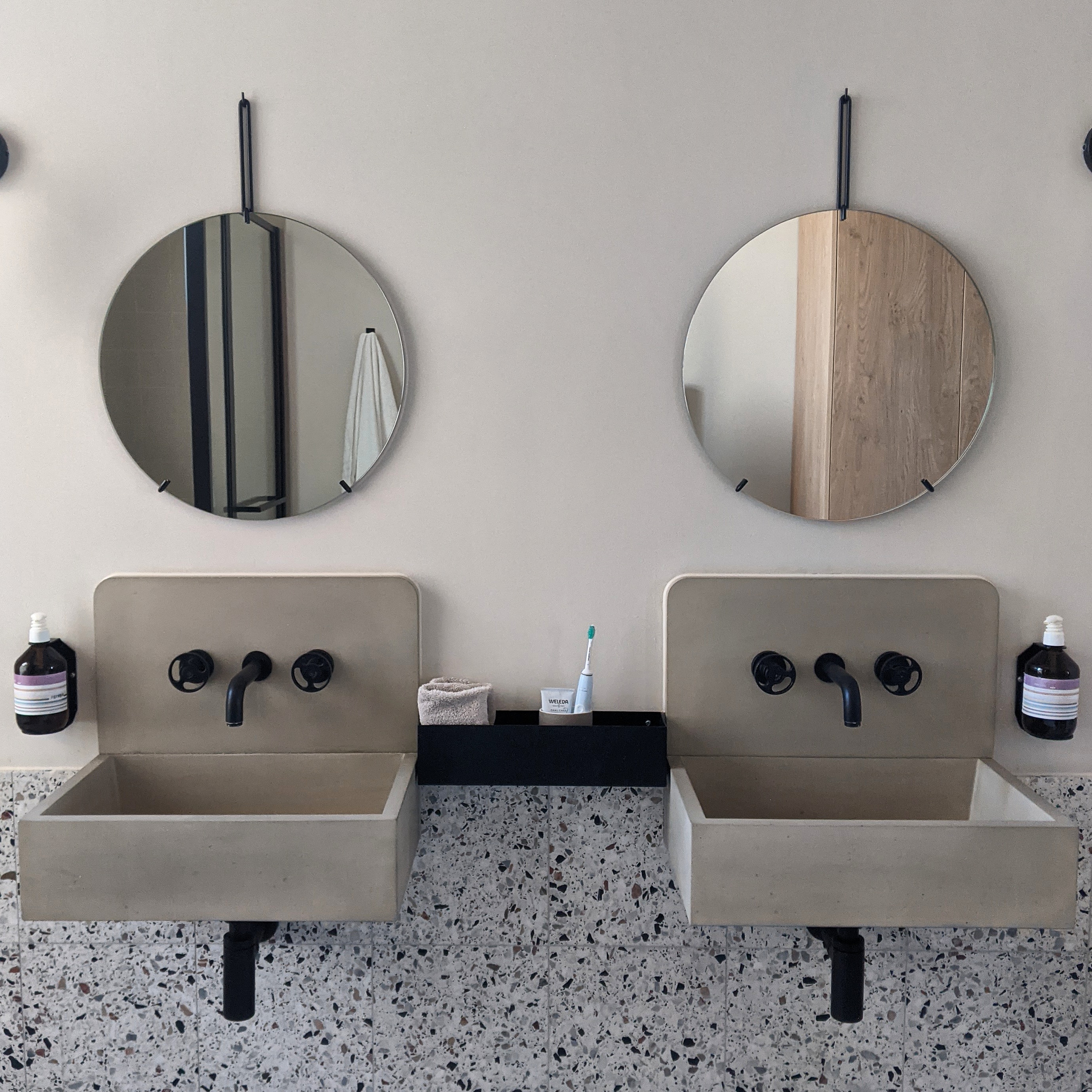 bathroom details at port hotel including circular mirrors and beautiful concrete sinks