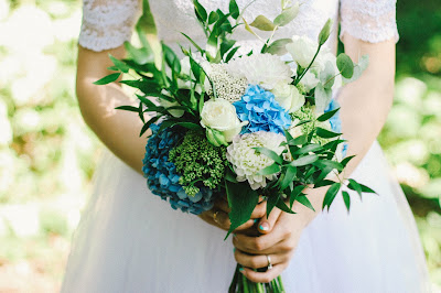 Novia llevando en las manos un ramo con flores azules