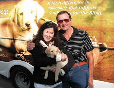 Nancy and Don Bloyer with yellow Lab guide dog puppy January in front of the Puppy Truck
