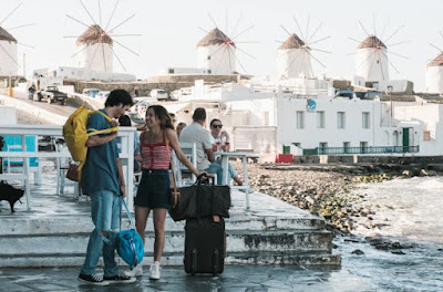 Protagonistas de la miniserie Un cuento perfecto con maletas delante de los molinos de Mykonos