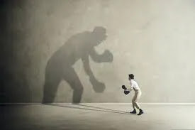 Hombre boxeando con su sombra gigante