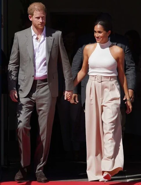 Meghan Markle wore a new ivory Kylin sweater by Anine Bing, and belted pleated wool-blend twill wide-leg pants by Brandon Maxwell