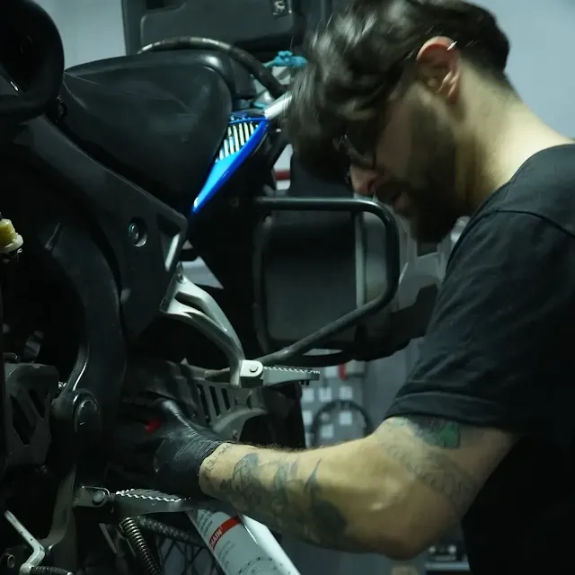 Técnico especializado aplicando lubricante YPF Röd en la cadena de una moto Corven durante el evento Corven Boxes
