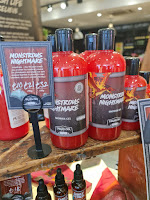 A close up of a row of bright red shower gel on cylindrical plastic bottles with a red and black label that says monstrous nightmare shower gel how to train your dragon x lush in white font on a bright background