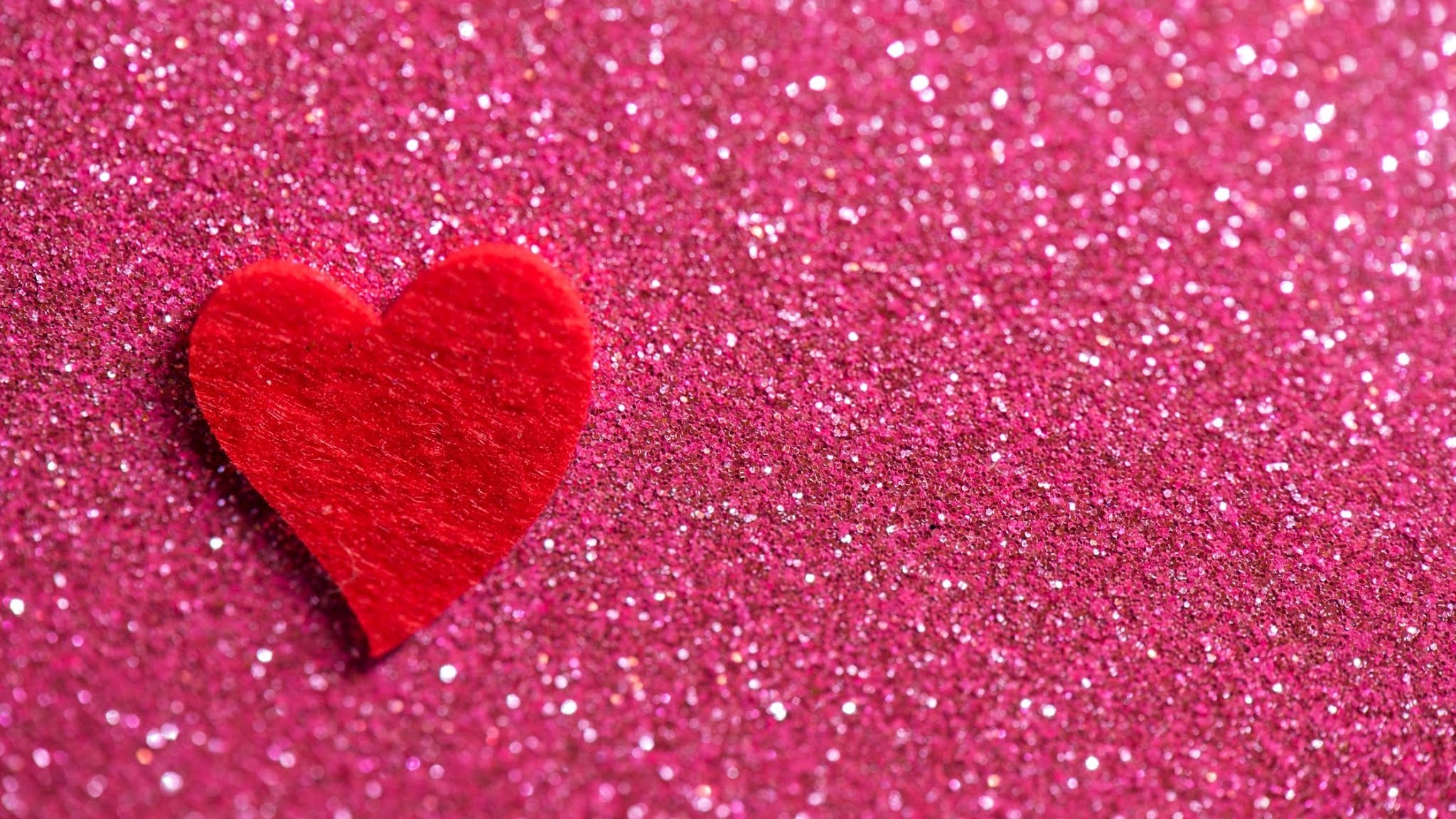 Red felt heart on a pink glitter background