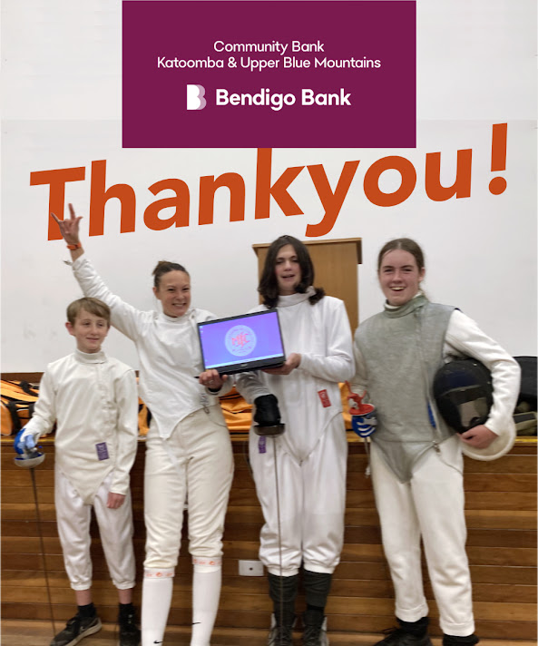 Four smiling fencers in a row, the two in the middle holding our cool new laptop open, so you can see the MFC logo on the screen. One fencer has her arm up making some kinda rock n roll gesture with her hand – coz Bendigo Bank rocks! In the background is a white wall with the word ‘Thankyou’ in warm orange, and at the top of the image is the Katoomba and Upper Blue Mountains Community Bendigo Bank Branch logo, which is those words, and a B symbol, in white on a maroon rectangular background. The mood is joyful!