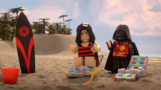Lego Darth Vader and Lego Emperor in summer clothes on the beach beside a surfboard with the Empire logo on