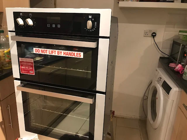 A photo taken mid installation of the oven showing the oven on a stand ready to be connected