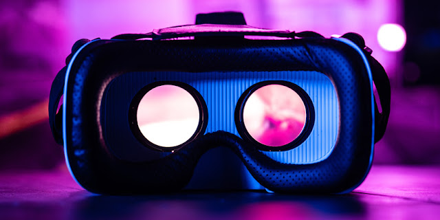 Close up of Virtual Reality glasses, black on a purple background.