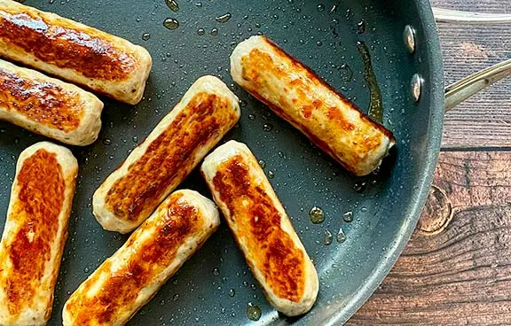 Sausages frying in a pan.