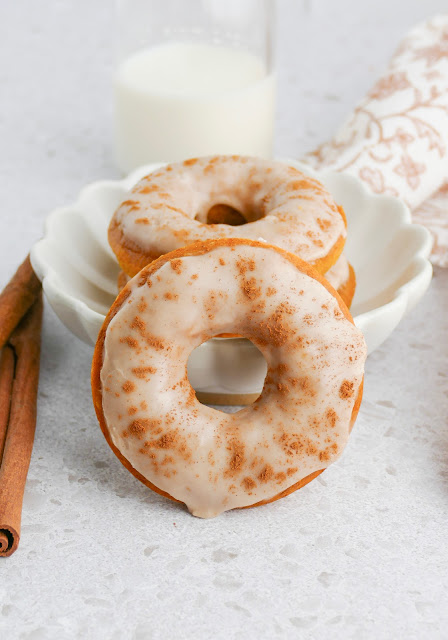 Baked Pumpkin Donut leaning against a white bowl.