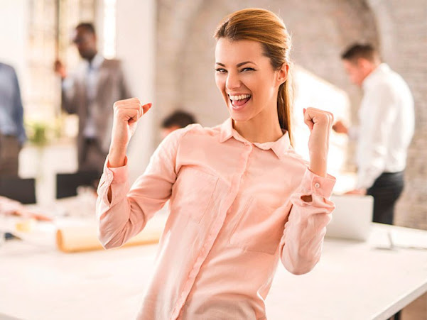 Mujer vestida con camisa rosa haciendo gesto de triunfo