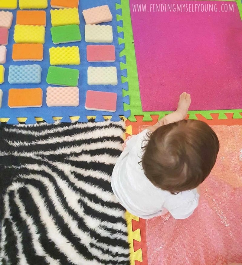 DIY sensory mat for babies made with foam mats and different fabrics.