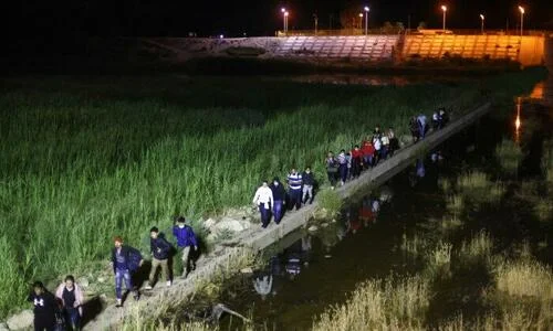 Illegal immigrants walk from Mexico into the United States on their way to await processing by the U.S. Border Patrol in Yuma, Ariz., on May 23, 2022. (Mario Tama/Getty Images)