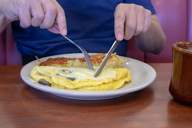Close-up of a plate featuring fluffy omelets served with golden waffles and a steaming mug of coffee, capturing a classic American breakfast setting
