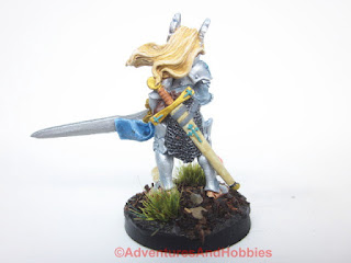 Rear view of a painted fantasy female elf warrior wielding a two-handed greatsword in 28mm scale for use in fantasy role-playing games and table top war games. Copyright Adventures And Hobbies.