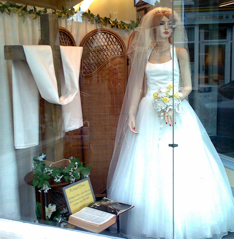 I found this odd juxtaposition of Cross and Wedding Dress in the window of