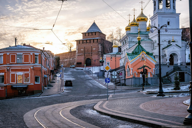 Дорога между старыми домами и церковью, а в отдалении башня кремля