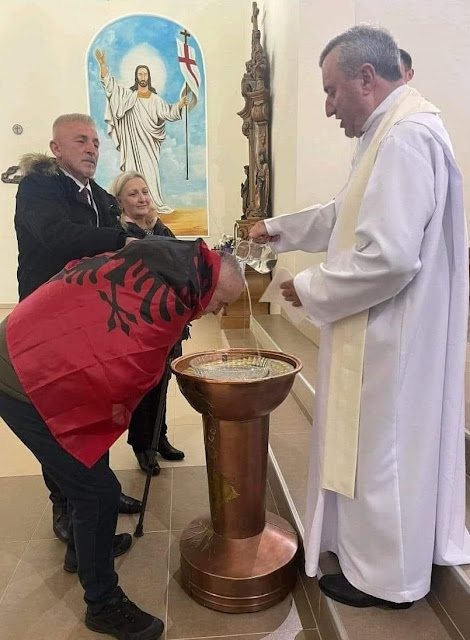 Kastriot Geci while being baptized wrapped in the Albanian flag